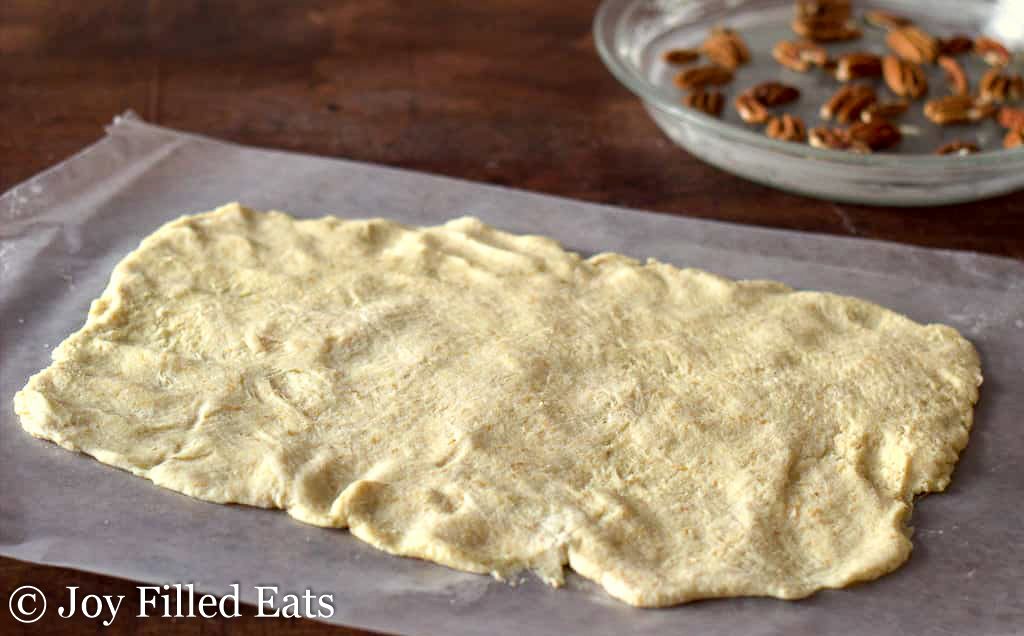 sticky bun dough rolled out onto parchment paper