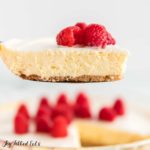 slice of keto lemon cheesecake topped with raspberries and a sour cream topping