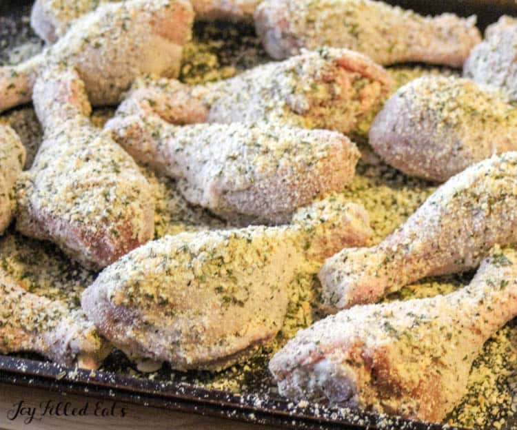 Chicken legs coated in a Parmesan crust before baking on a sheet pan