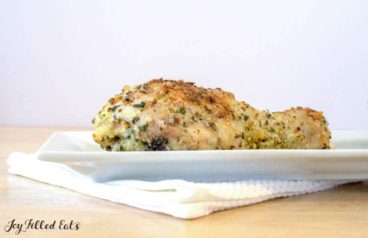Parmesan crusted baked chicken leg on white plate