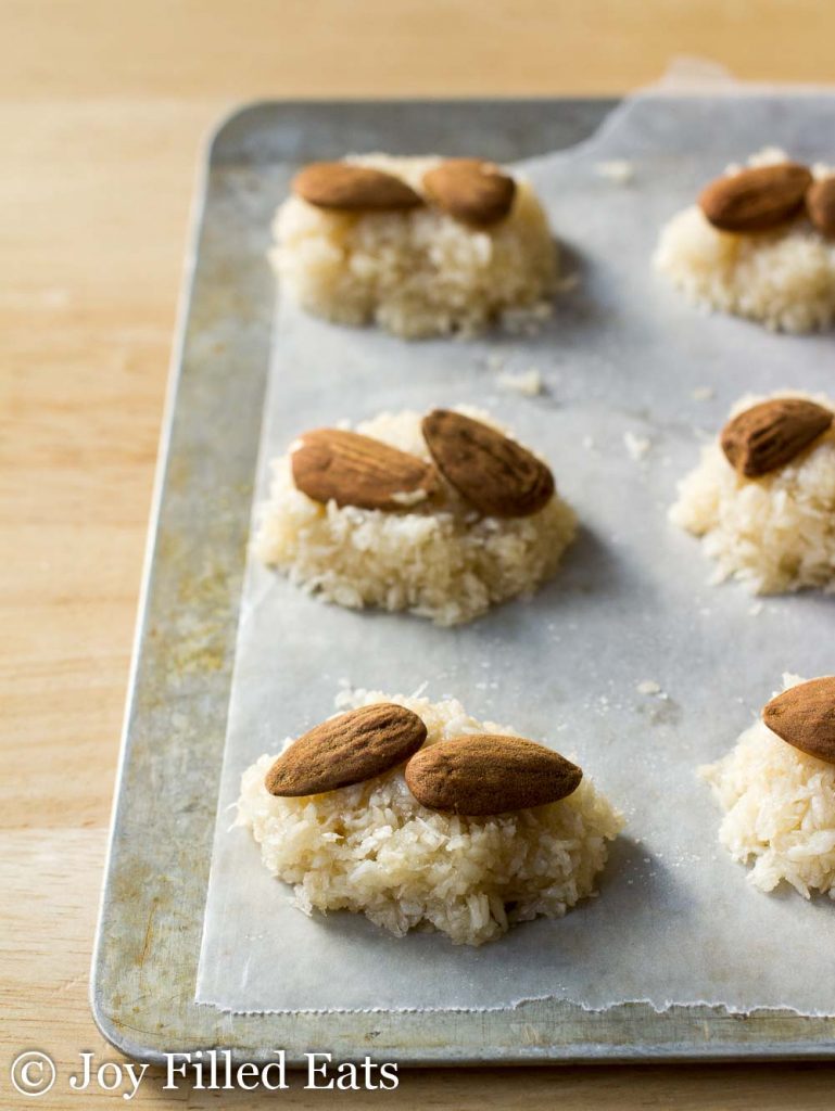 dough for homemade almond joy candies topped with almonds lined on a sheet pan lined with parchment paper