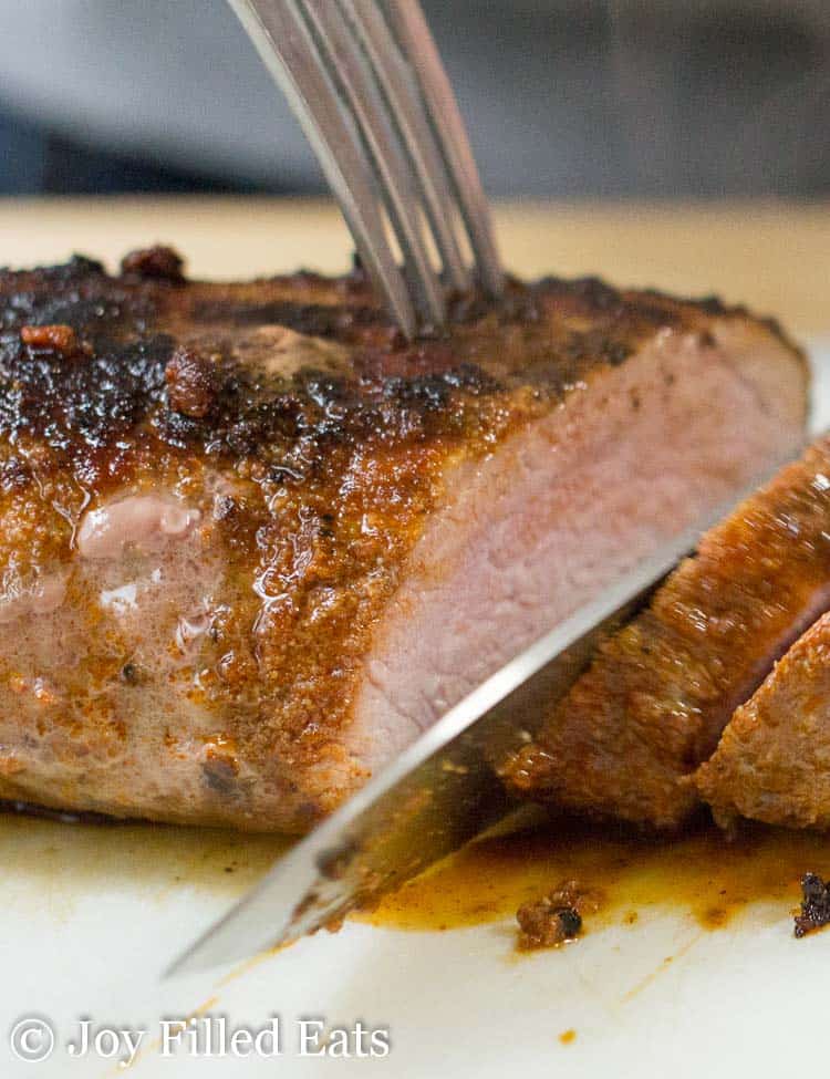 pork tenderloin close up being sliced with chefs knife