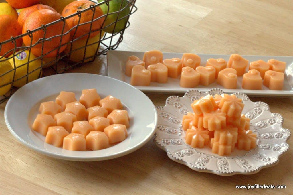 three white plates each with a different shaped sugar free orange creamsicle gummies