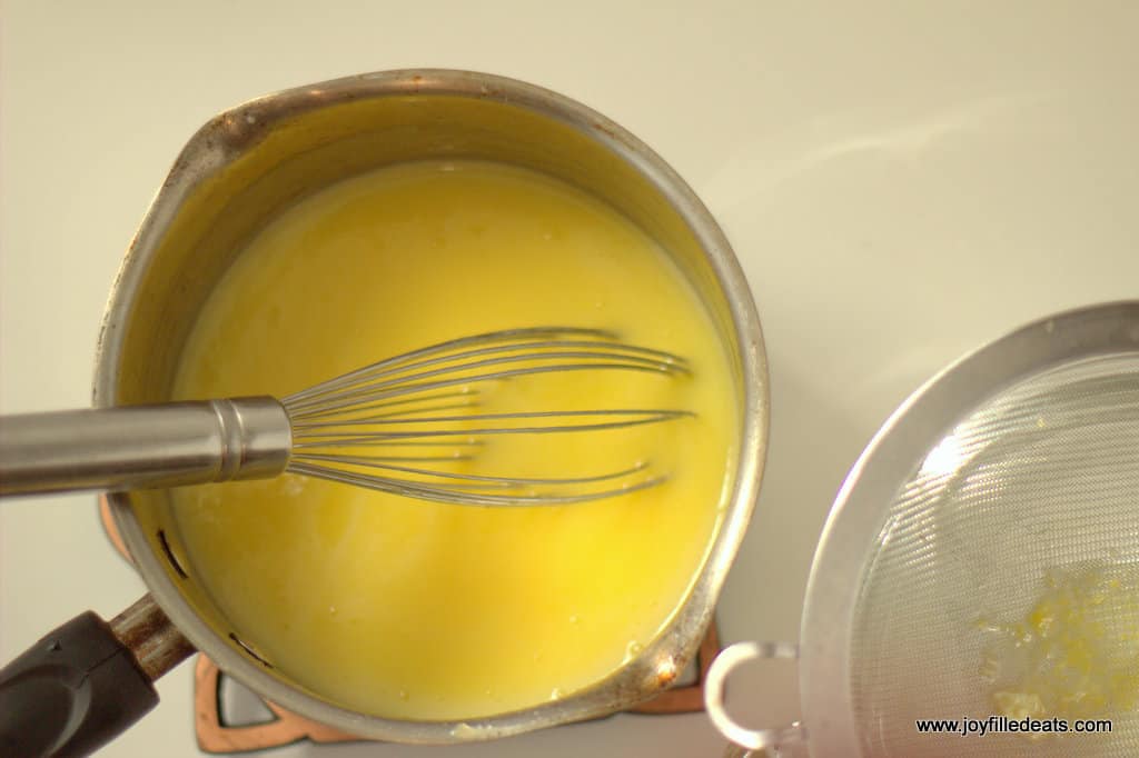 overhead view of saucepan filled with creamy lemon dessert sauce with a whisk