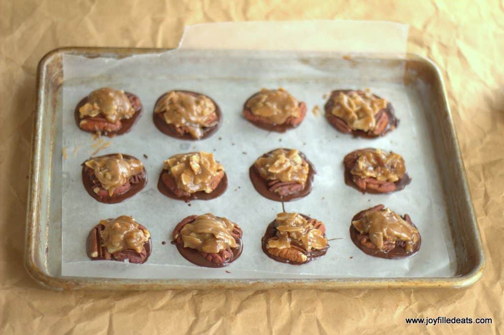 toasted coconut toffee pecan turtle candies lined on a sheet pan before being covered in chocolate