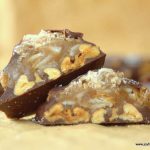 two halves of a toasted coconut toffee pecan turtle candy leaning on each other