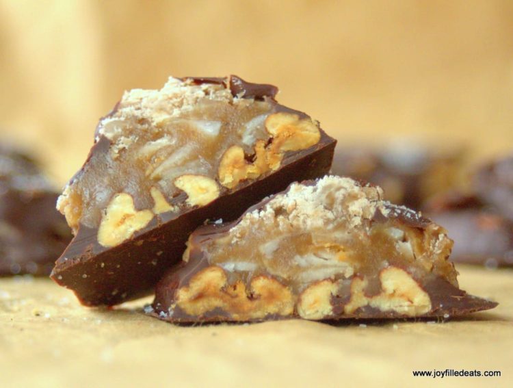 two halves of a toasted coconut toffee pecan turtle candy leaning on each other