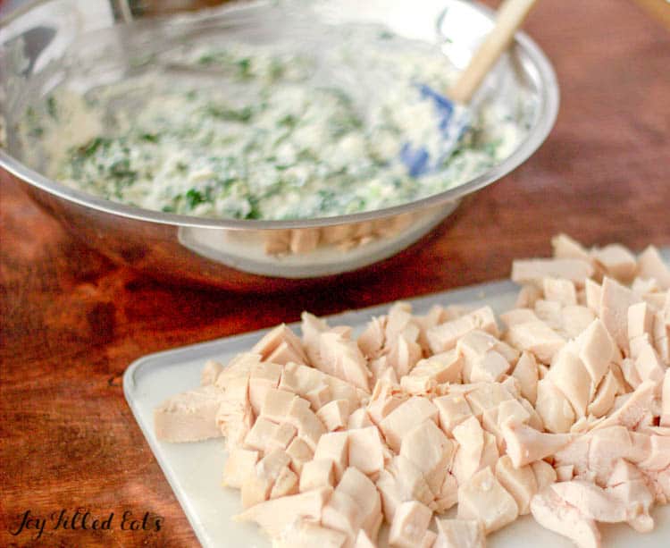 Cutting board of chicken pieces next to mixing bowl of homemade caesar seasoning