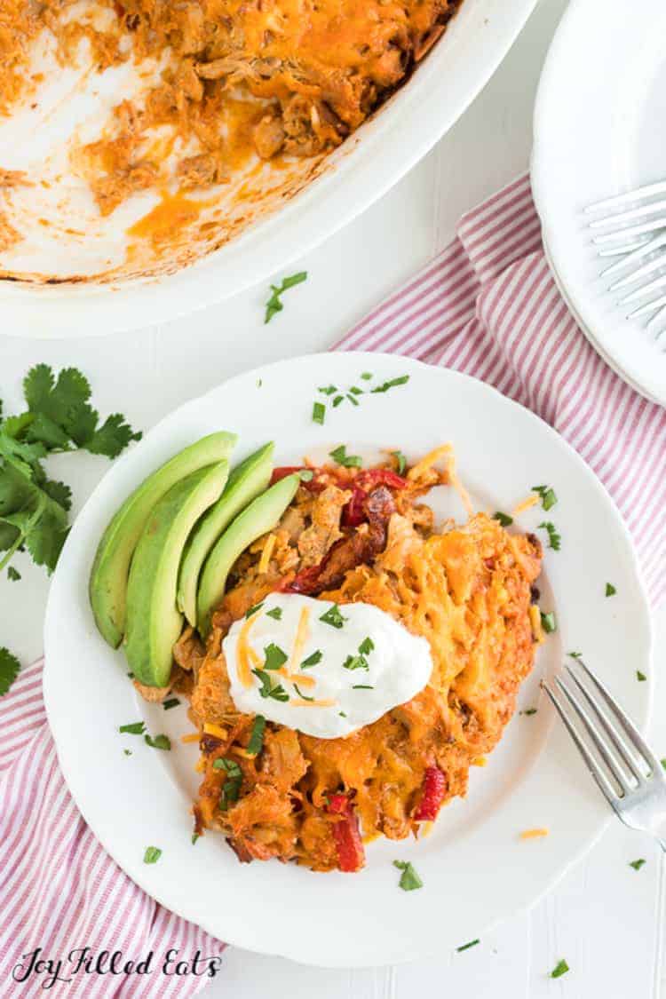 chicken fajita casserole serving on a plate topped with sour cream and served with avocado slices from above