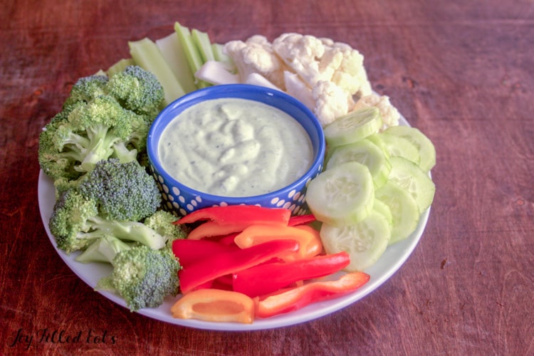 small dish of chive dip placed center on platter surrounded by cut vegetables