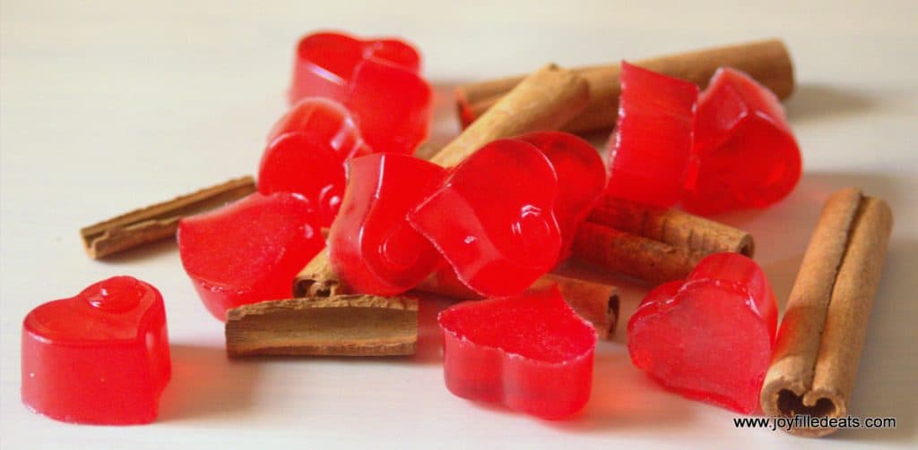 pile of sugar free red hot gummies placed on scattered cinnamon sticks