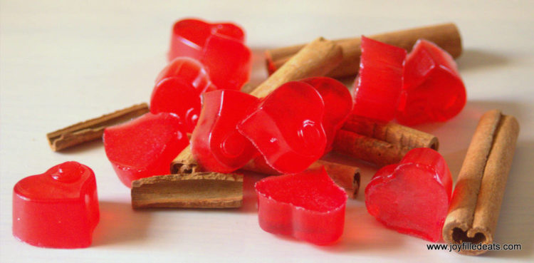 pile of sugar free red hot gummies placed on scattered cinnamon sticks