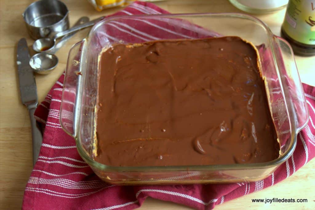 melted chocolate layered on top of peanut butter cookie batter in a square baking dish