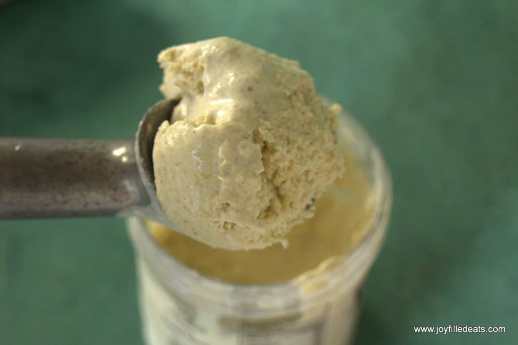 ice cream scoop full of sugar free pistachio ice cream above a mason jar of ice cream