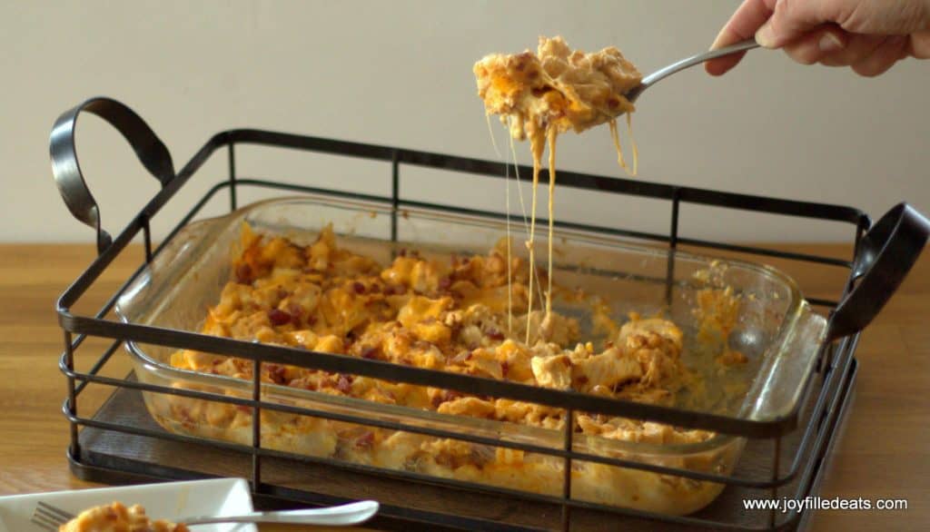 hand scooping a serving of barbecue chicken bacon casserole for glass casserole dish in a wire casserole basket