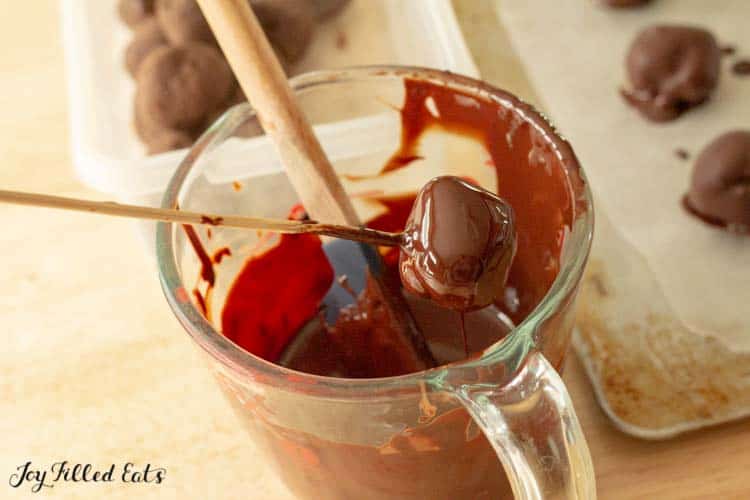 skewers with brownie ball being dipped into pitcher of chocolate coating