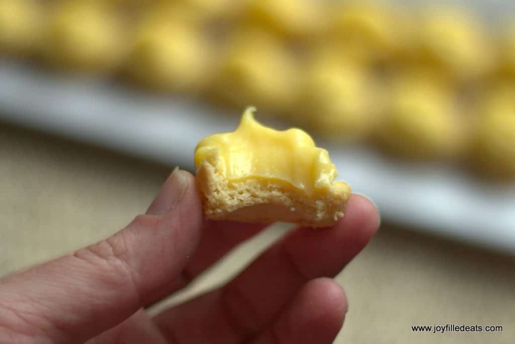 hand holding a creamy lime curd tart with a bite missing