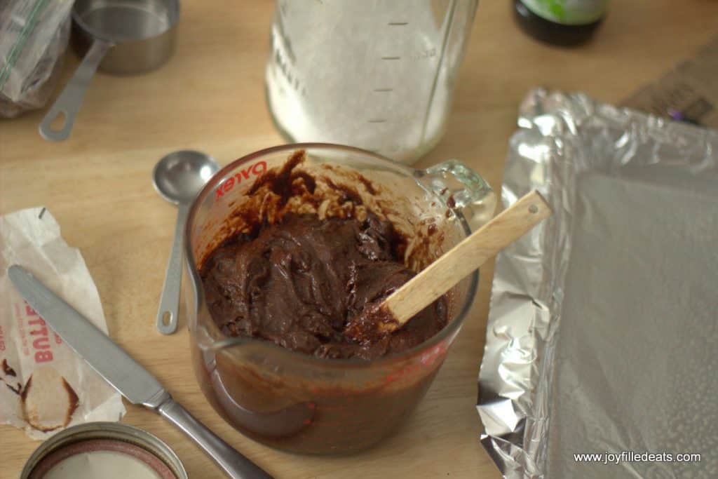 large measuring cup filled with brownie batter with a spatula