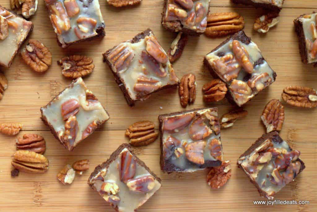overhead view of pecan praline brownies arranged on a wooden surface surrounded with scattered pecans