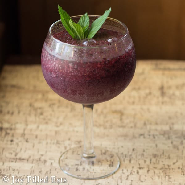 large steam wine glass filled with a frozen blueberry mojito topped with a mint garnish