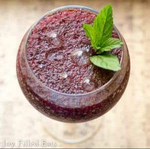 overhead view of glass with frozen blueberry mojito topped with mint