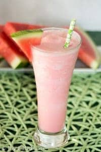 tall glass filled with watermelon smoothie with a slice of watermelon on the rim of glass