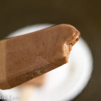 hand holding a mocha fudgesicle with bite missing from corner