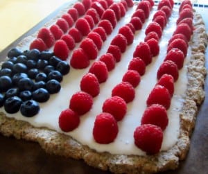 close up on red, white and blue flag cake topped with blueberries and raspberries