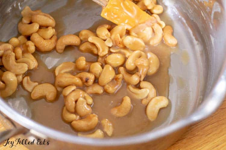 whole cashews being mixed into salted caramel topping