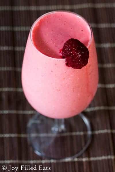 close up on a frozen raspberry cocktail mocktail with a strawberry garnish on the rim
