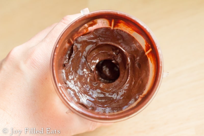 overhead view of hand holding a jar full of chocolate ganache