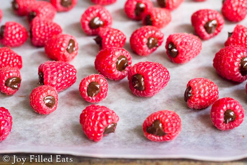 raspberries filled with chocolate ganache arranged on a sheet of parchment paper