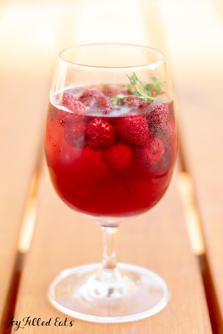 a glass of keto sangria with raspberries and thyme