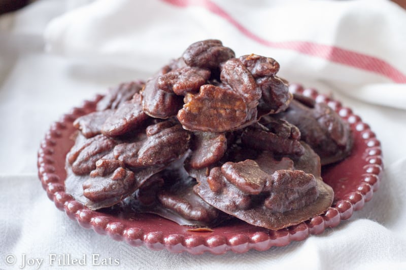 pile of chocolate pecan pralines on a red plate