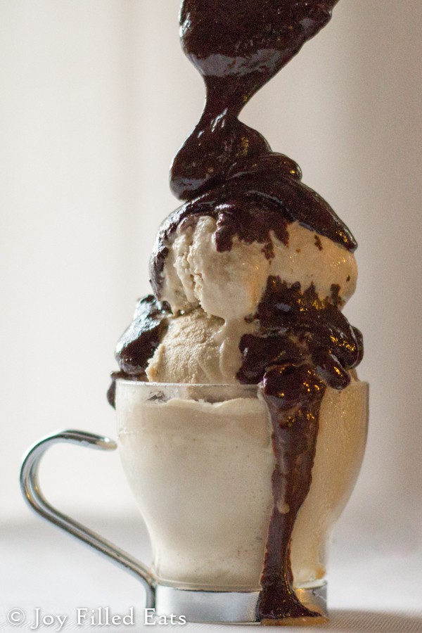 three ingredient hot fudge being poured onto a scoops of ice cream in a small glass mug