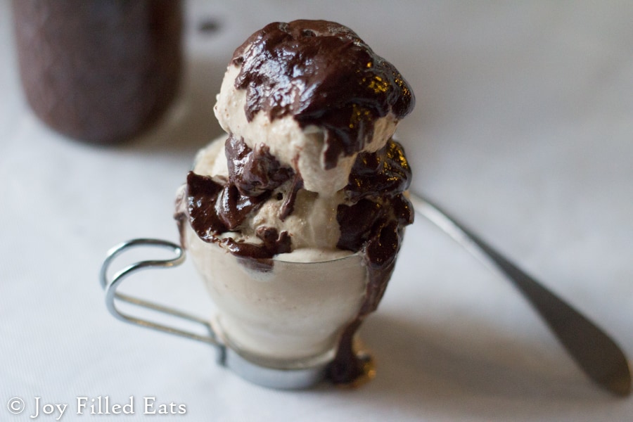 three ingredient hot fudge covering scoops of ice cream in a small glass cup next to a spoon