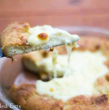 serving spatula lifting slice of keto cheese calzone pie from pie plate