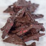 dark chocolate raspberry truffle bark lined in a pile on a marble surface