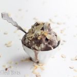 small bowl of almond joy ice cream with a spoon topped with shaved almonds