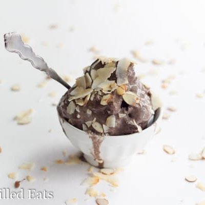 small bowl of almond joy ice cream with a spoon topped with shaved almonds