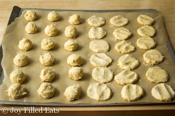 parchment lined cookie sheet filled with cheese danish dough balls with half flattened into round shapes