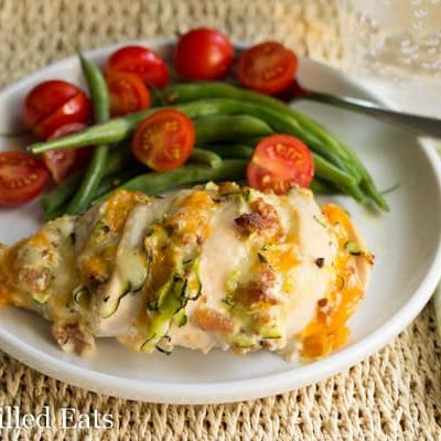Four Cheese Bacon Hasselback Chicken on a white plate with green beans and tomatoes