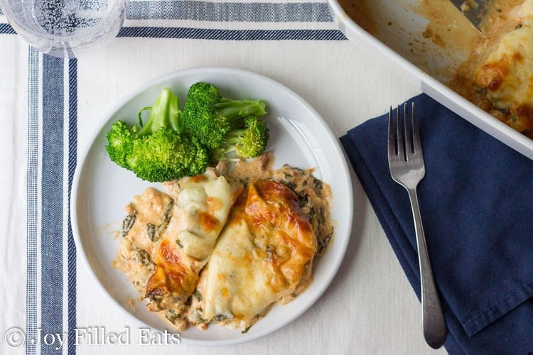 overhead view of Tuscan chicken casserole served with broccoli florets on a white plate next to a fork
