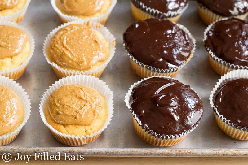 baking sheet lined with cupcakes, half are topped with a peanut butter filling and another are topped with melted chocolate