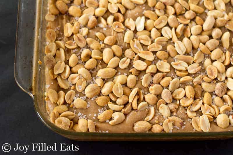 overhead view of baking dish filled with peanut butter cake with caramel icing and topped with peanuts