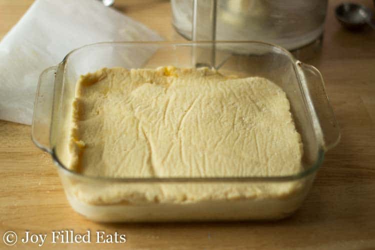 baking dish of sopapilla cheesecake batter layers