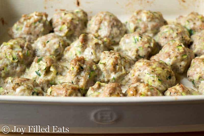 small sized meatballs baked in the bottom of a white casserole dish