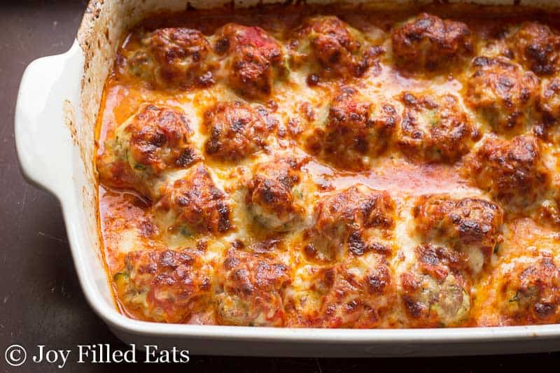a white casserole dish with a baked meatball casserole