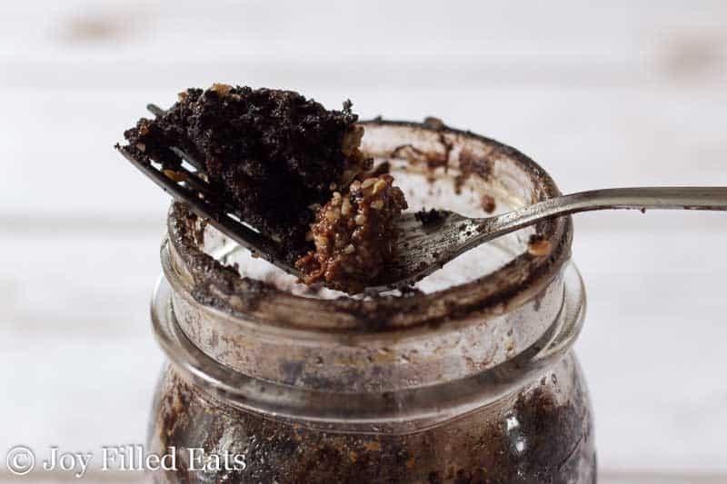bite of chocolate pecan mason jar cake on a fork resting on the rim of a mason jar
