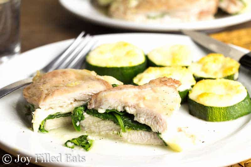 garlic Parmesan zucchini pieces on a white plate with two pieces of stuffed chicken